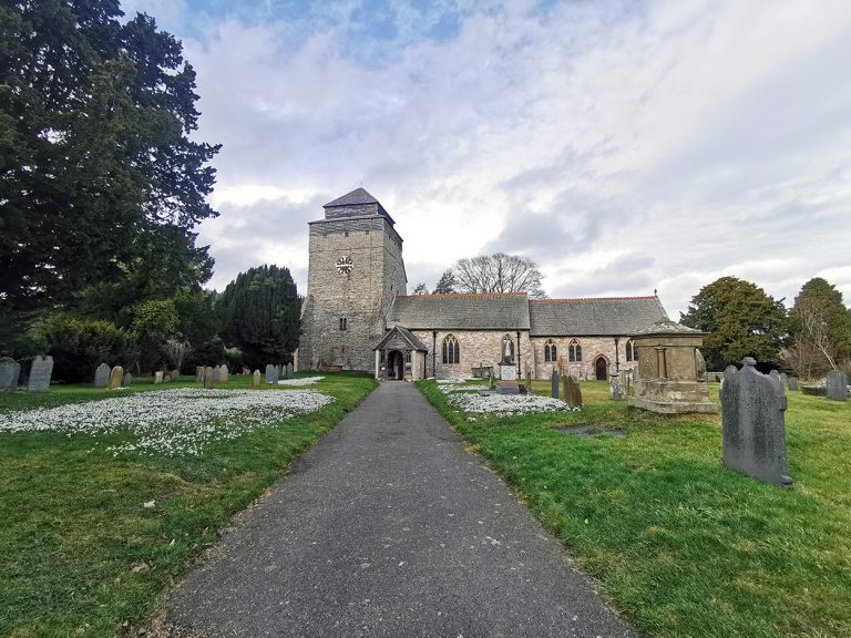 A village church surrounded by gravestones and snowdrops.